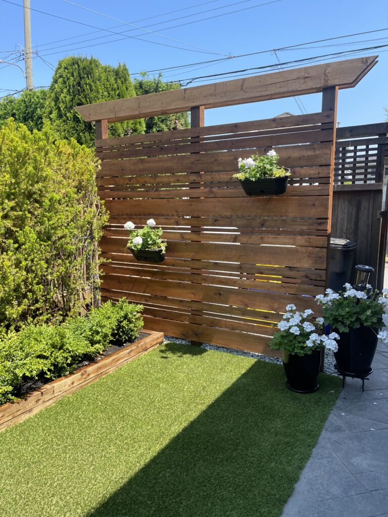 wood privacy screen, wood border, artificial grass, boxwoods, geraniums